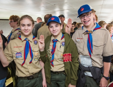 Three boy scouts raising their hands in a scout salute for a photo at the top of the Gateway Arch