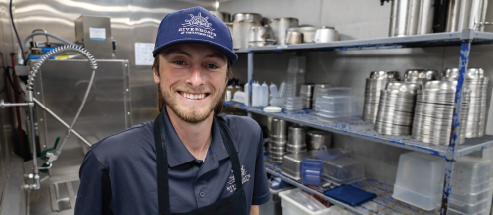 A Dishwasher smiles and poses for a photo in the galley on the Riverboats at the Gateway Arch